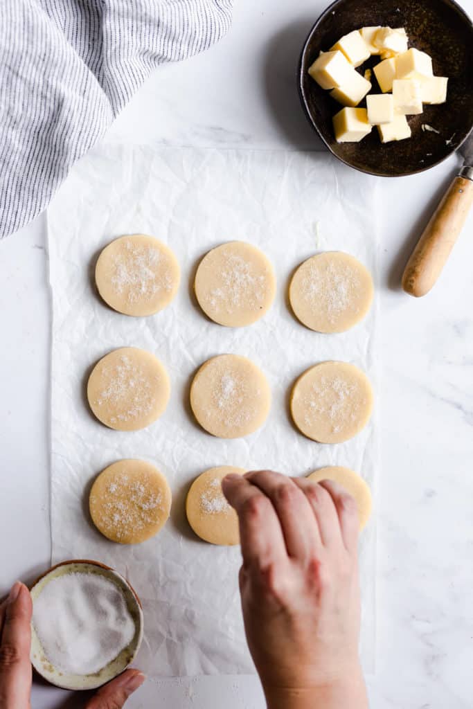 overhead shot of a person sprinkling sugar on cookies