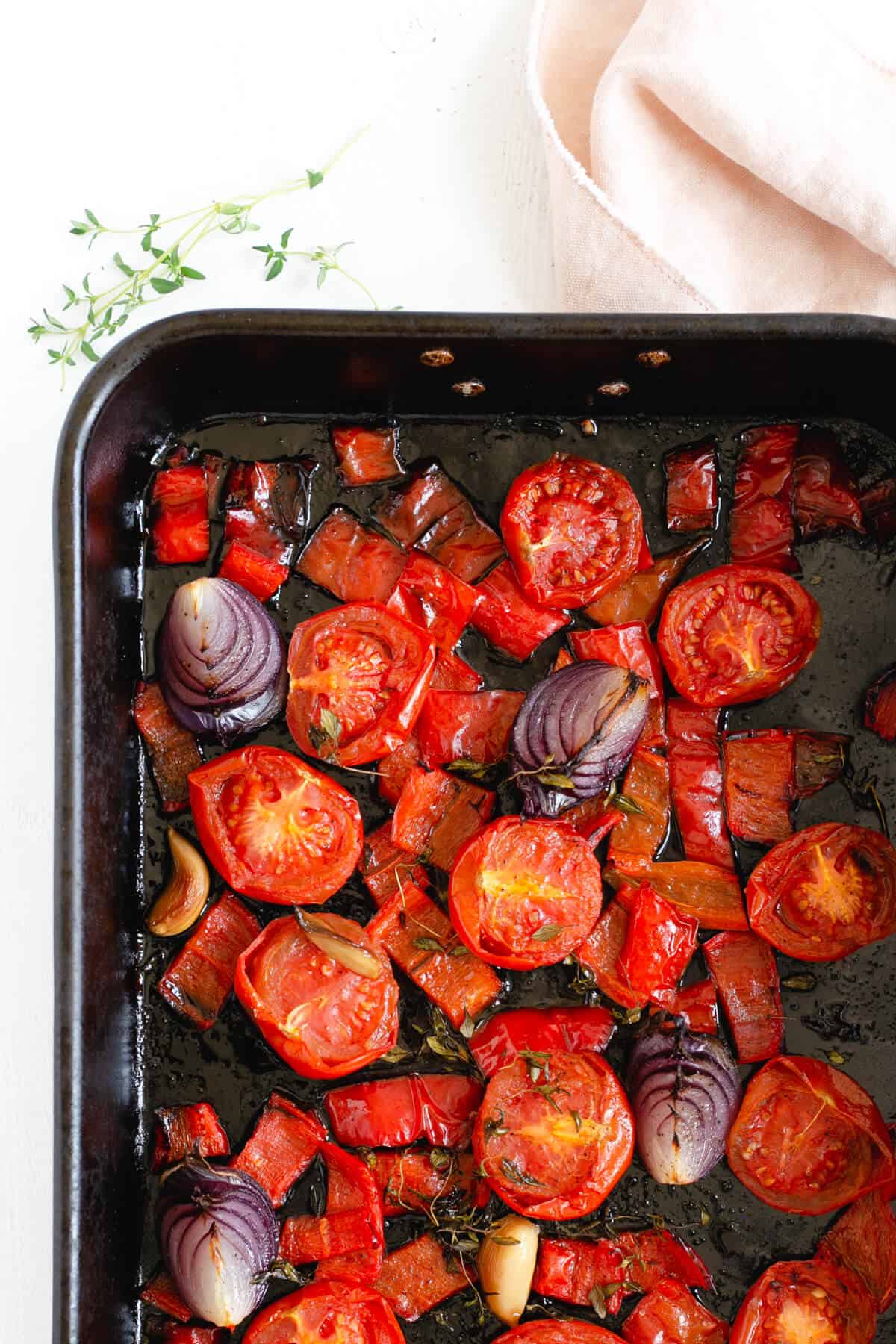 Roasted tomatoes, red peppers and red onions in a roasting tin