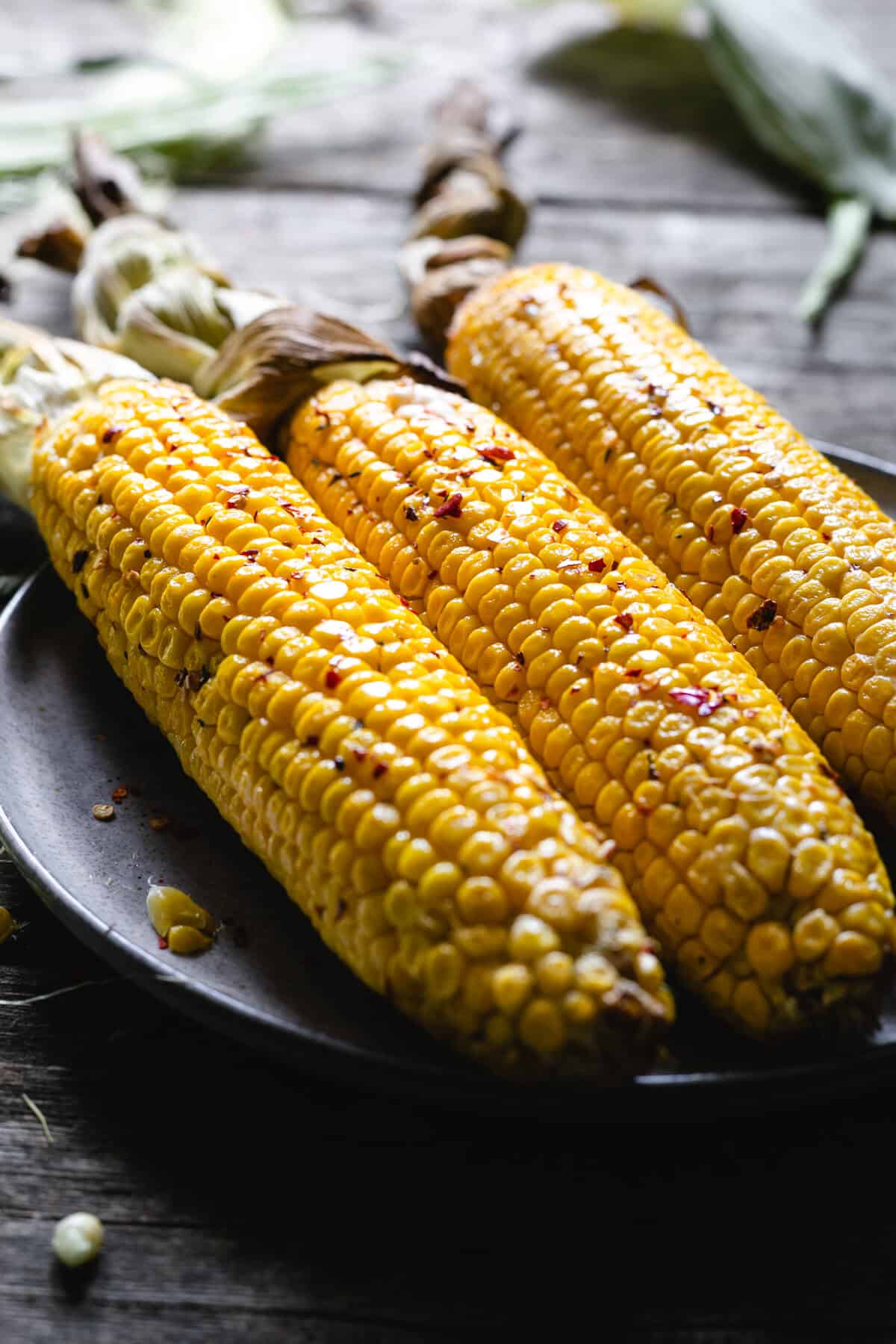 Three large corn cobs in chilli butter on a plate
