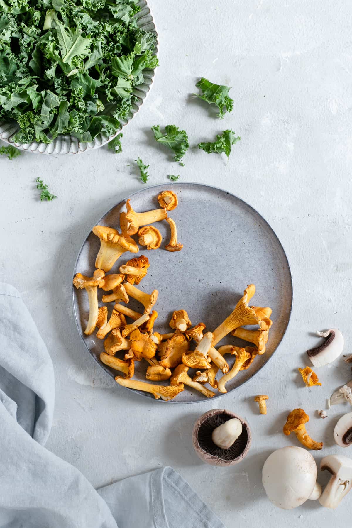 Plate with fresh curly kale and plate with chanterelle mushrooms