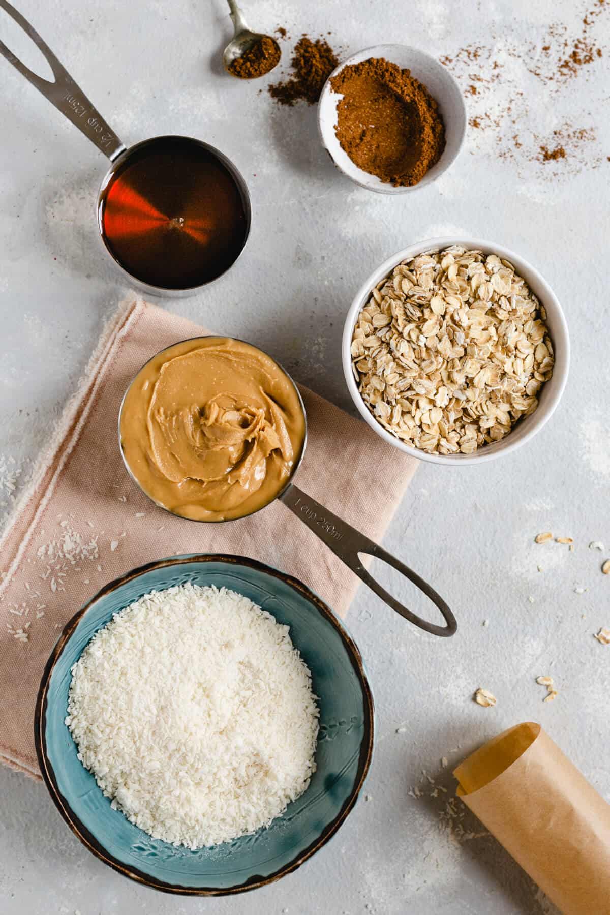 Overhead shot of bowl of oats, shredded coconut, peanut butter, maple syrup and mixed spice