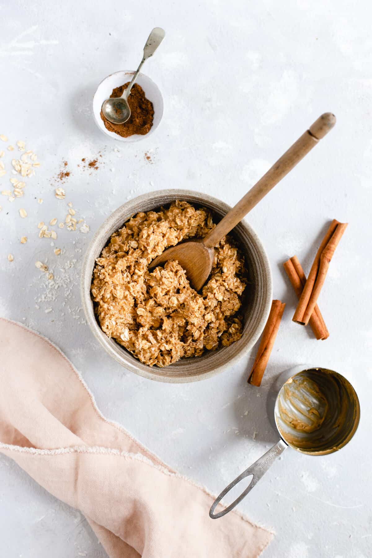 Overhead shot of bowl with oats, coconut shreds and peanut butter mixture with wooden spoon