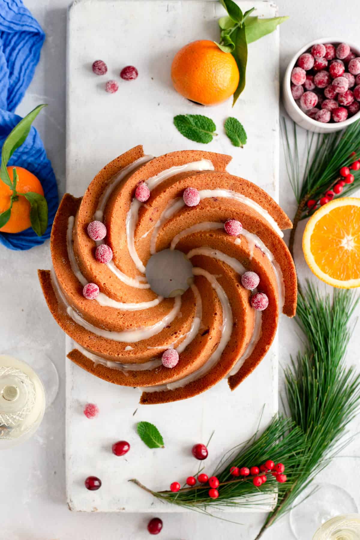 Overhead shot of orange and cranberry bundt cake, drizzled with icing and topped with sugared cranberries