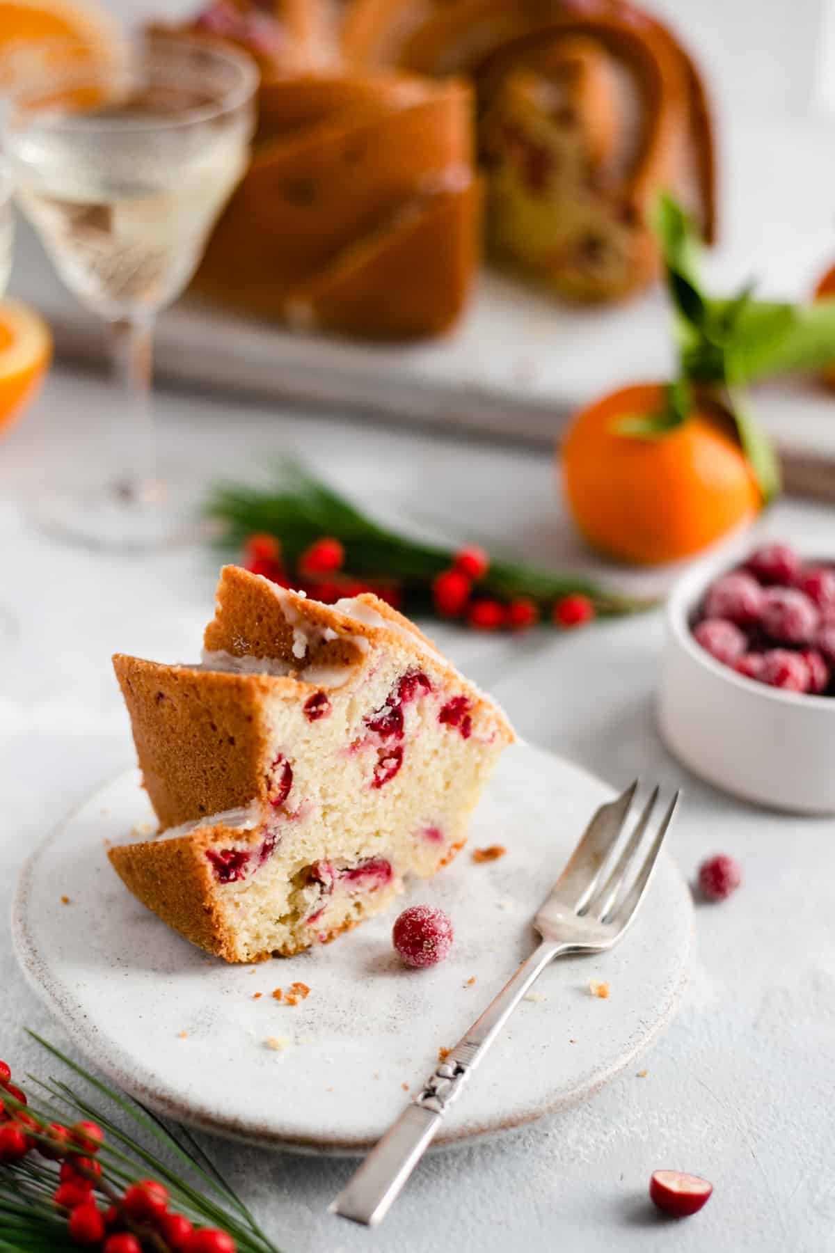 Slice of orange and cranberry cake on a plate with a small fork