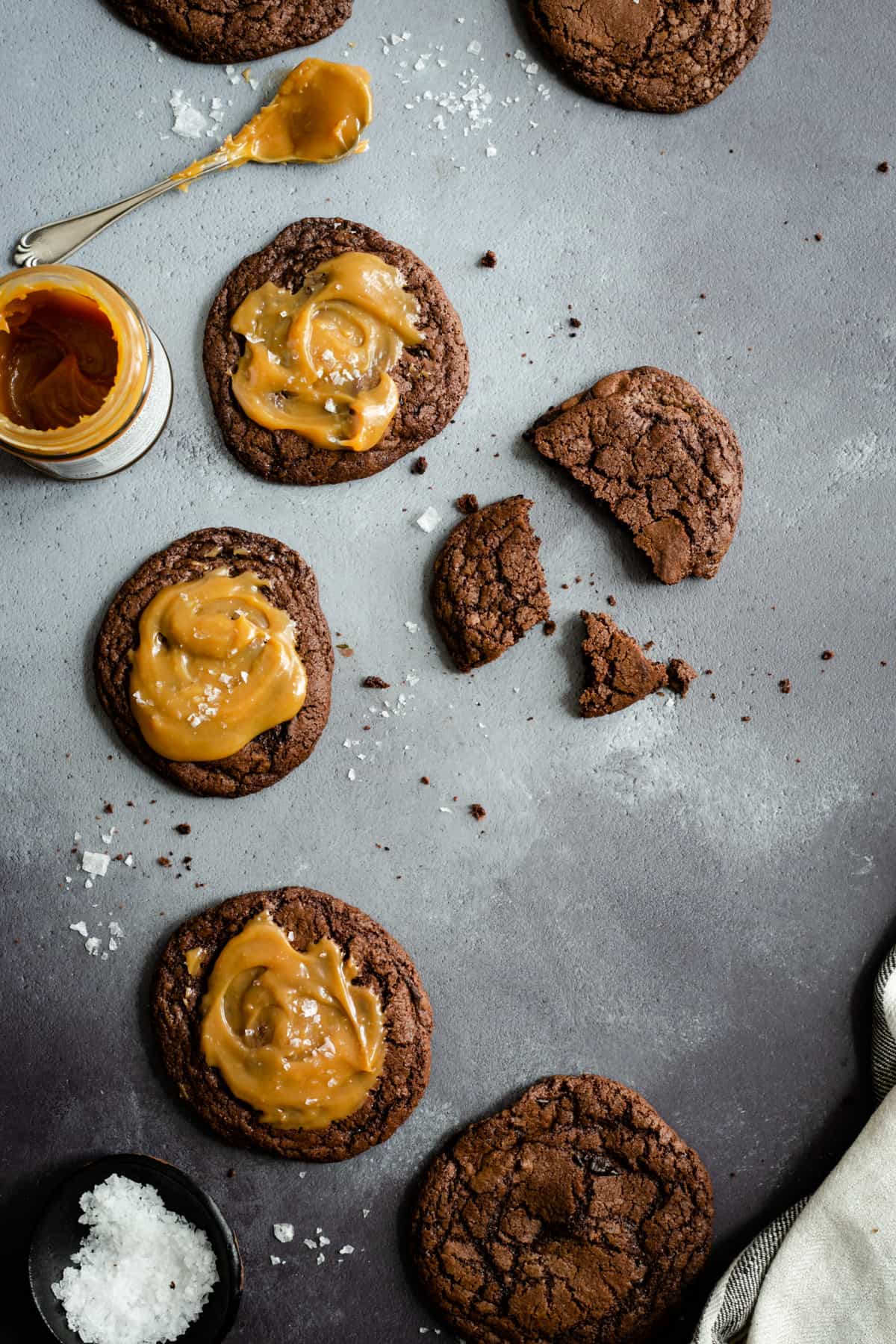 Overhead shot of chocolate salted caramel cookies with a small jar of caramel on site
