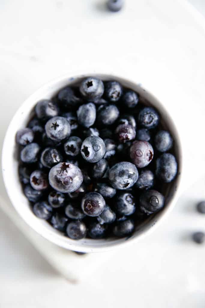 Overhead shot of small white bowl with fresh blueberries
