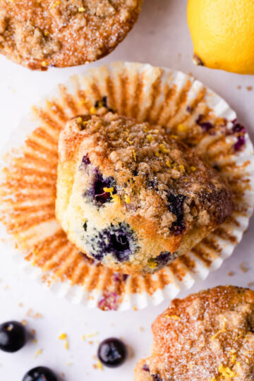 an individual lemon and blueberry muffin with its wrapper underneath.