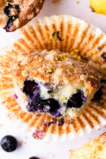 a single blueberry muffin with bite taken out showing blueberries inside.