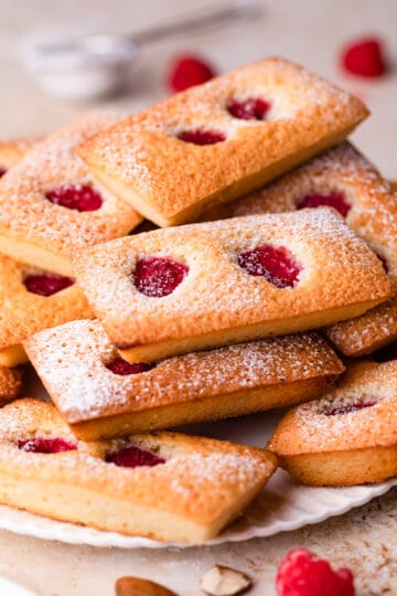 stack of almond financiers with raspberries and dusted with icing sugar.