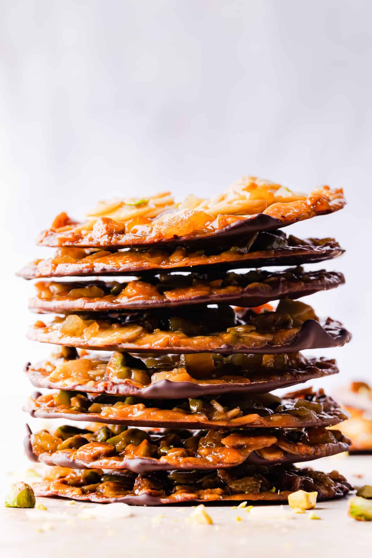 tall stack of thin florentine cookies with flaked almonds and pistachios.