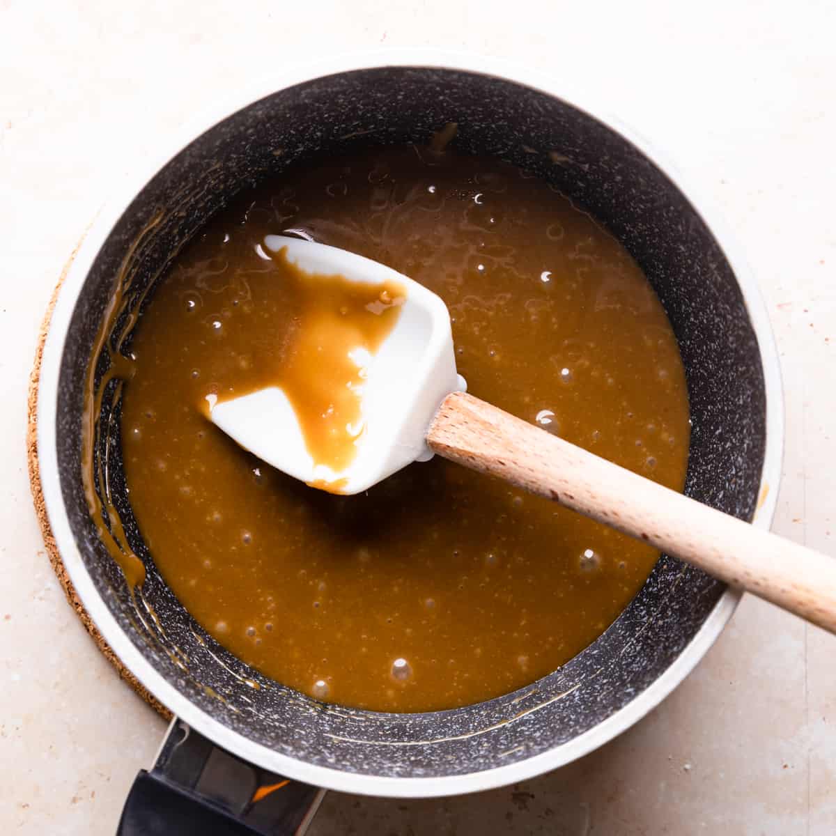 small saucepan with caramel sauce for almond florentines and white spatula inside of the pan.