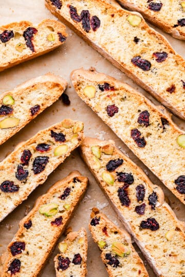 slices of biscotti with dried cranberries and some nuts arranged on a baking paper.