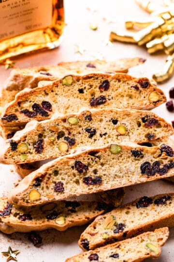 amaretto and cranberry biscotti stack with gold ribbon in the background.