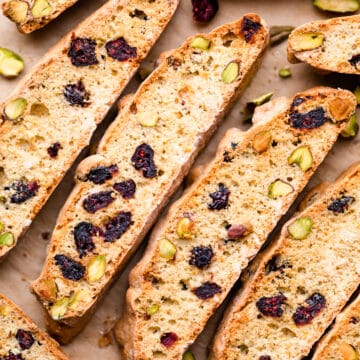 slices of individual biscotti with cranberries on a brown baking paper.