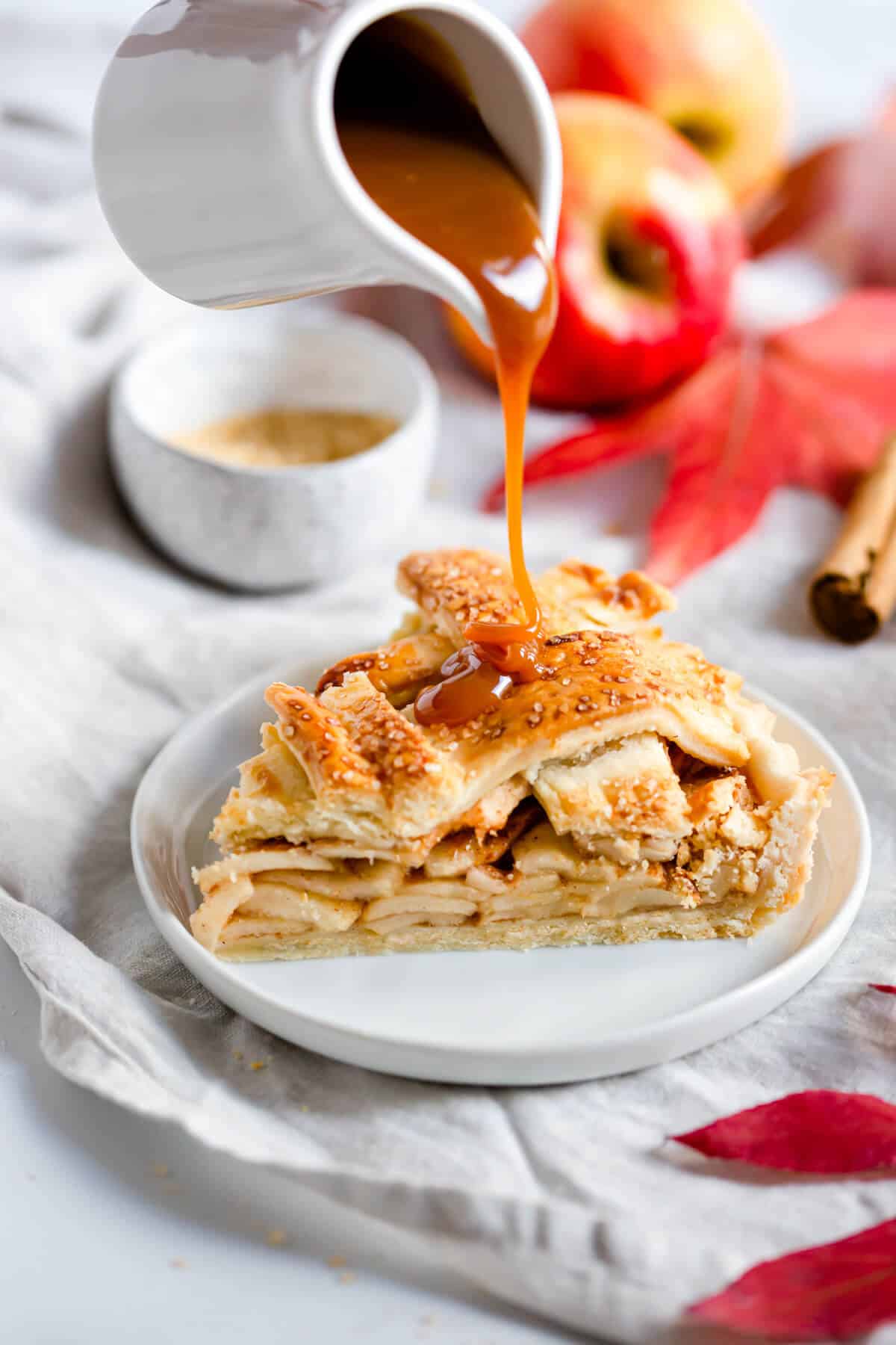a slice of an apple pie with caramel being poured on it