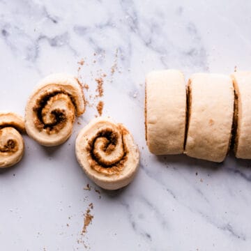 slices of dough rolls with cinnamon sugar filling on a white marble surface.