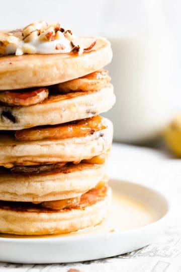 Super close up showing stack of pancakes with hazelnuts and caramelised bananas