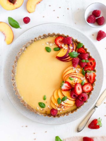 Vegan peach tart with gluten-free crust, topped with summer berries