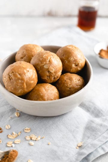 Side shot of small bowl filled with coconut and peanut butter spiced energy bites