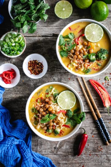 Overhead shot of two bowls of Thai style pumpkin laksa topped with roasted chickpeas and fresh mint