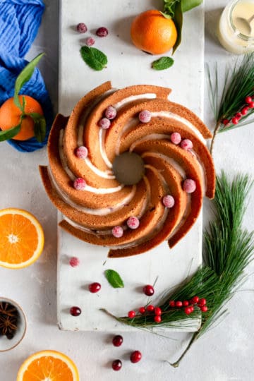 An overhead shot of a whole orange and cranberry cake with drizzle