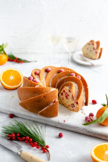 Side shot of orange and cranberry bundt cake with a slice cut out
