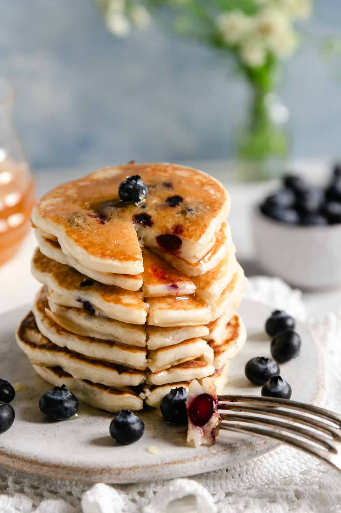 Straight ahead shot of stack of golden blueberry pancakes with a segment cut out