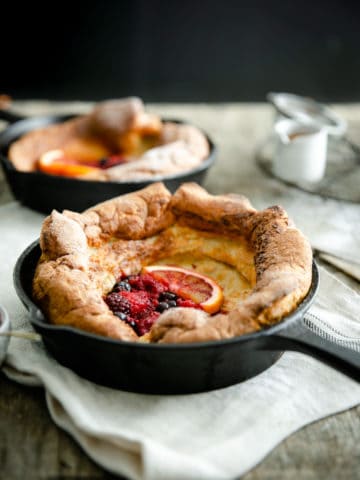 A small skillet with mixed berry dutch baby