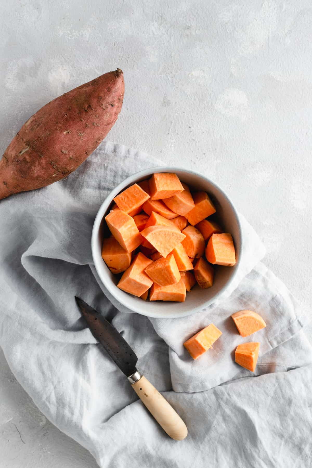 small bowl with chunks of sweet potato and a hand knife on side