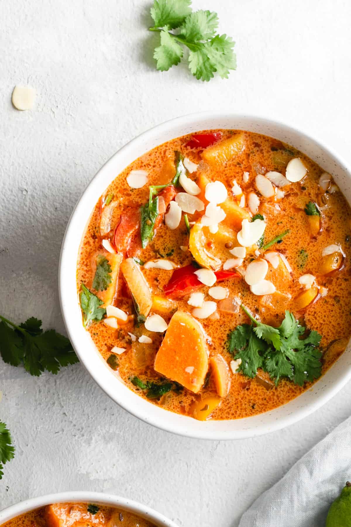 overhead shot of a single bowl with sweet potato curry topped with toasted almonds and coriander