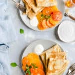 overhead shot of two plates with crepes, citrus, yogurt and honey drizzle