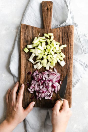 Overhead shot of chopped celery and onion on a wooden chopping board