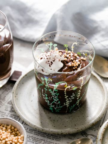 A small glass filled with vegan chocolate pudding and topped with whipped coconut cream