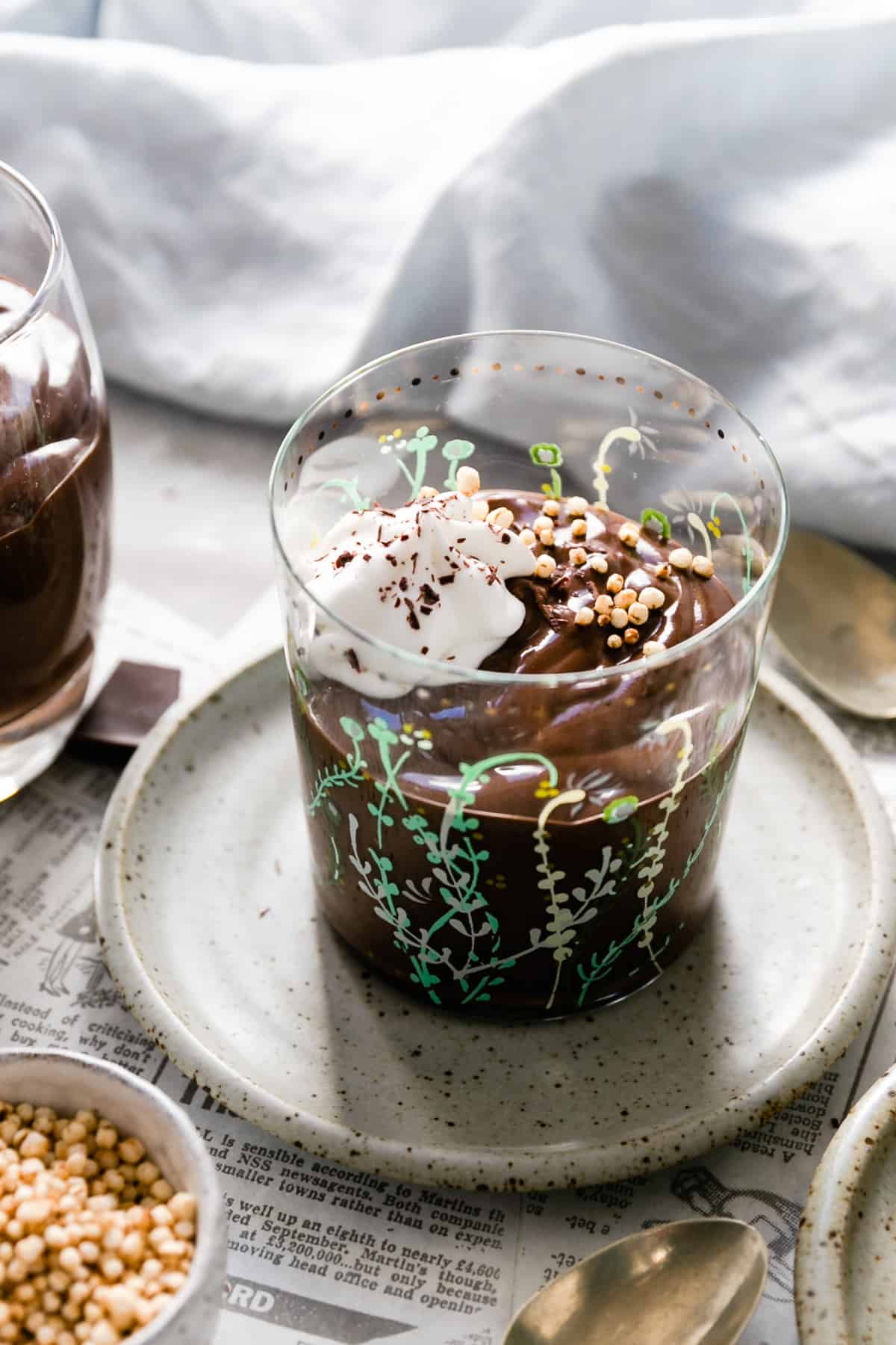 A small glass filled with vegan chocolate pudding and topped with whipped coconut cream
