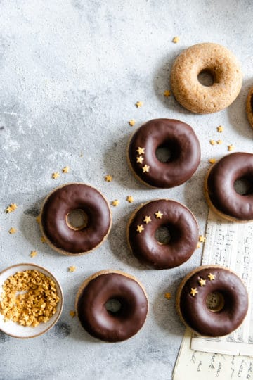 baked doughnuts with chocolate glaze and small bowl of star-shaped sprinkles