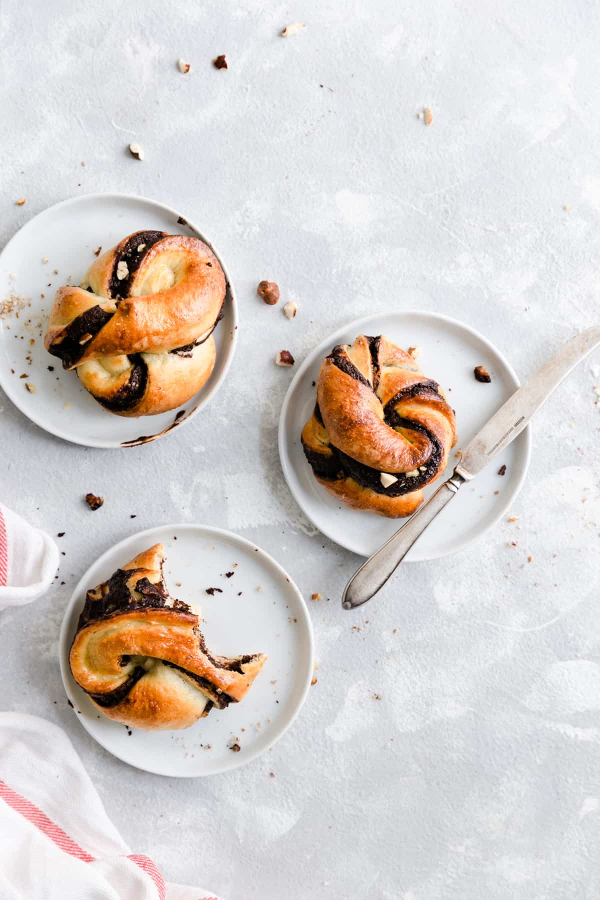 Overhead shot of 3 individual chocolate hazelnut babka buns resting on small white plates
