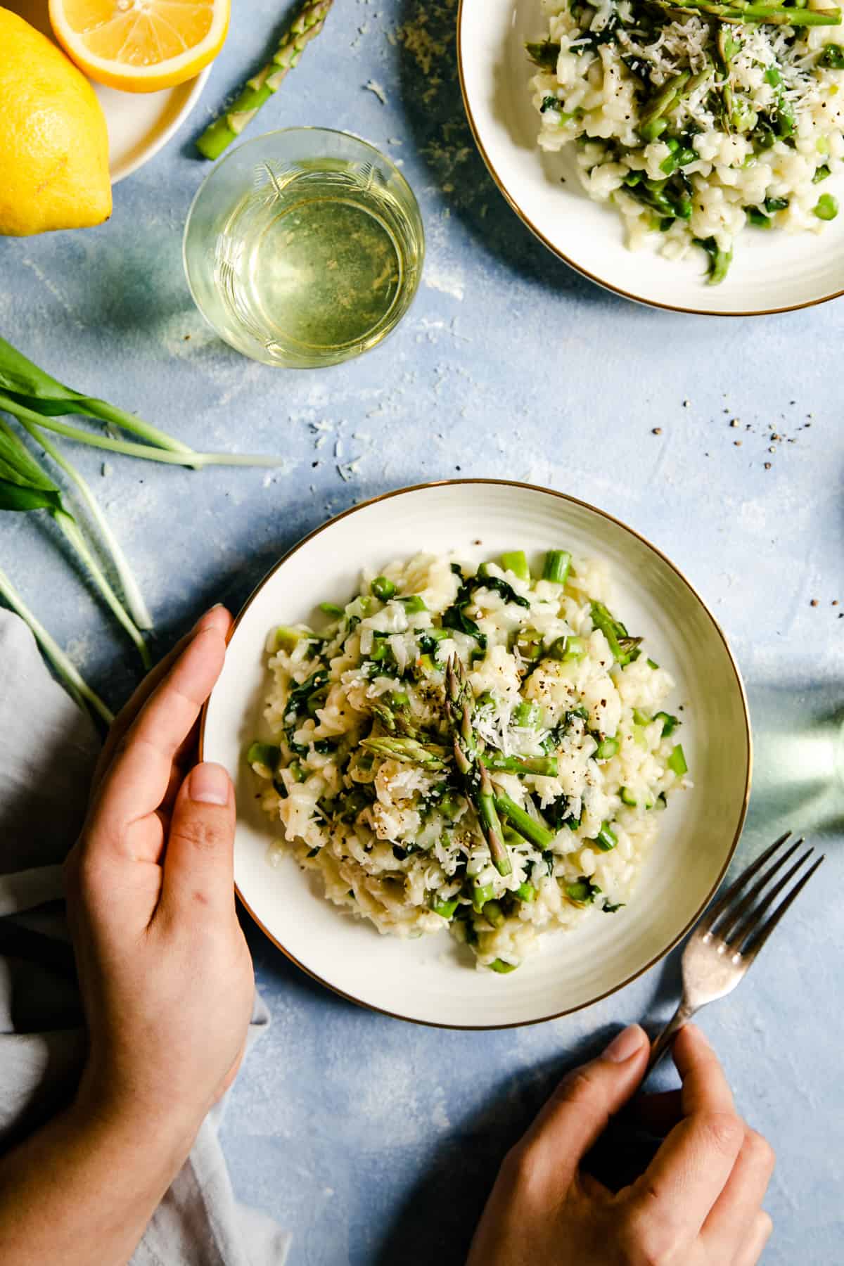 overhead shot of person holding a bowl with wild garlic and asparagus risotto 