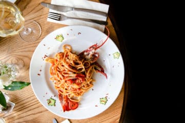 overhead shot of white plate filled with lobster linguine