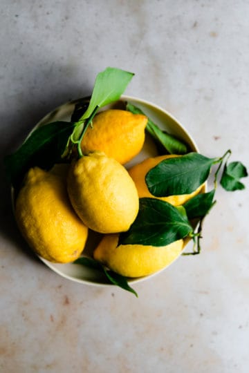 overhead shot of Sorrento lemons with leaves in a small bowl
