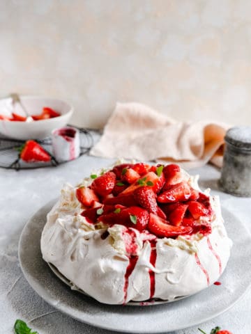 straight ahead shot of strawberry Pavlova on a large plate dusted with icing sugar