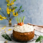 Vegan carrot cake topped with cream cheese frosting and some carrot tops