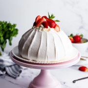45 degree angle view of the strawberry pavlova on pink cake stand