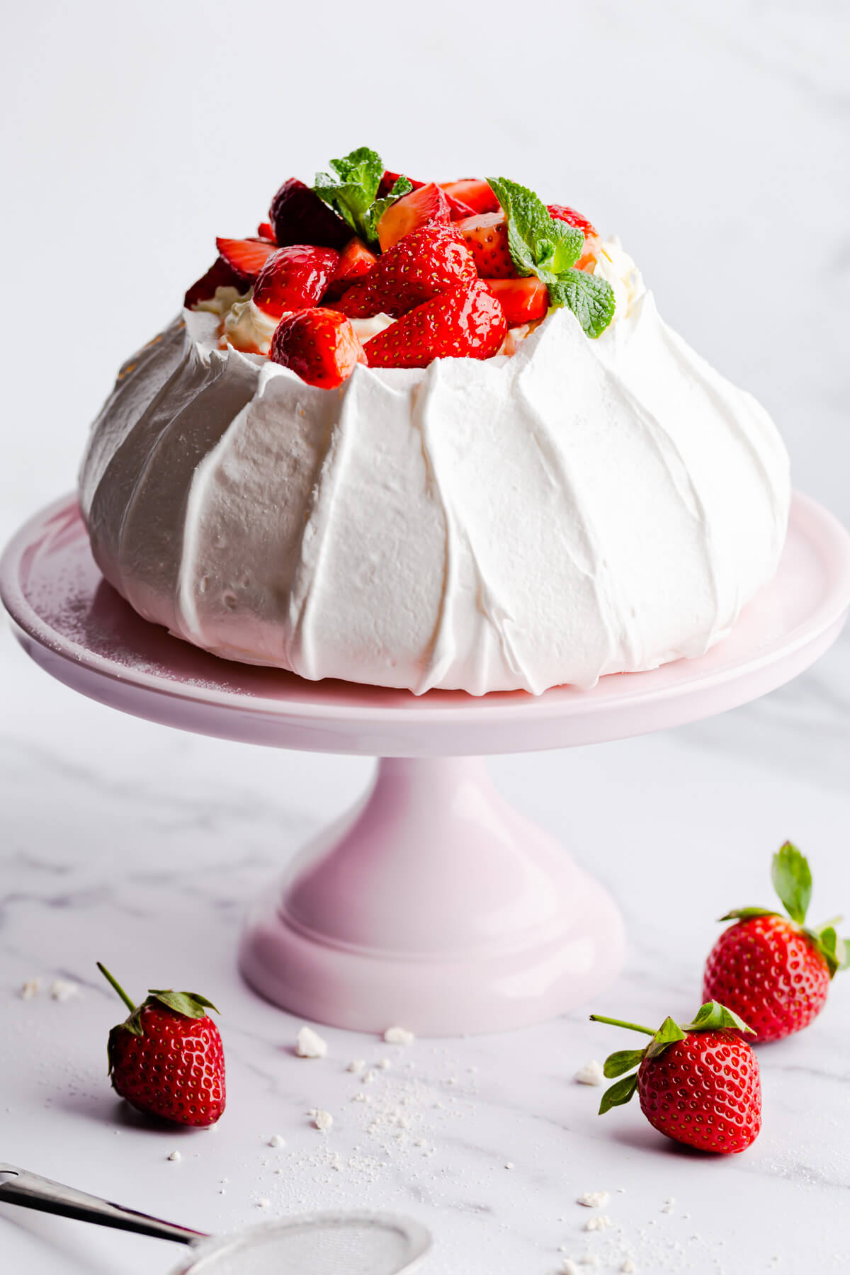 side close up at a baked pavlova topped with cream and fresh strawberries