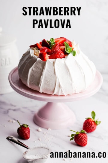 45 degree angle view of strawberry pavlova on cake stand with text overlay