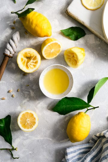 overhead shot of a small bowl of lemon juice with lemon halves and whole lemons around it