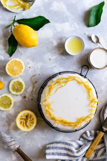 overhead shot of a zesty lemon cake with icing and candied lemon peel on top