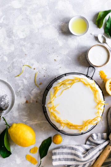 overhead shot of a zesty lemon cake with icing and candied lemon peel on top