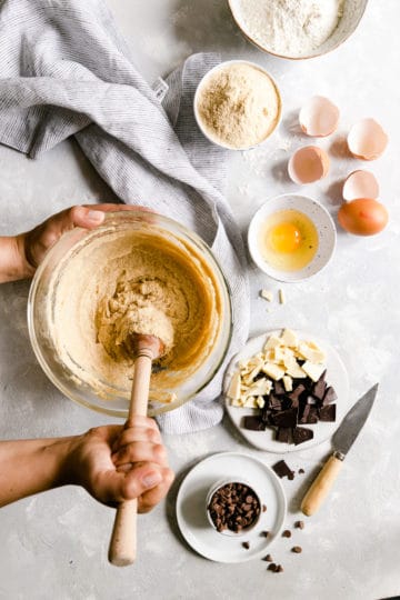 overhead shot of a person mixing the ingredients for a cookie dough in a large bowl