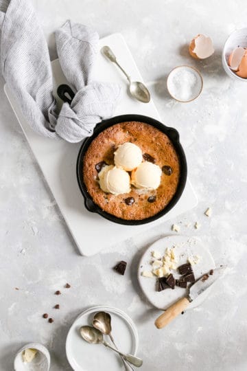 overhead shot of skillet cookie topped with 3 scoops of vanilla ice cream