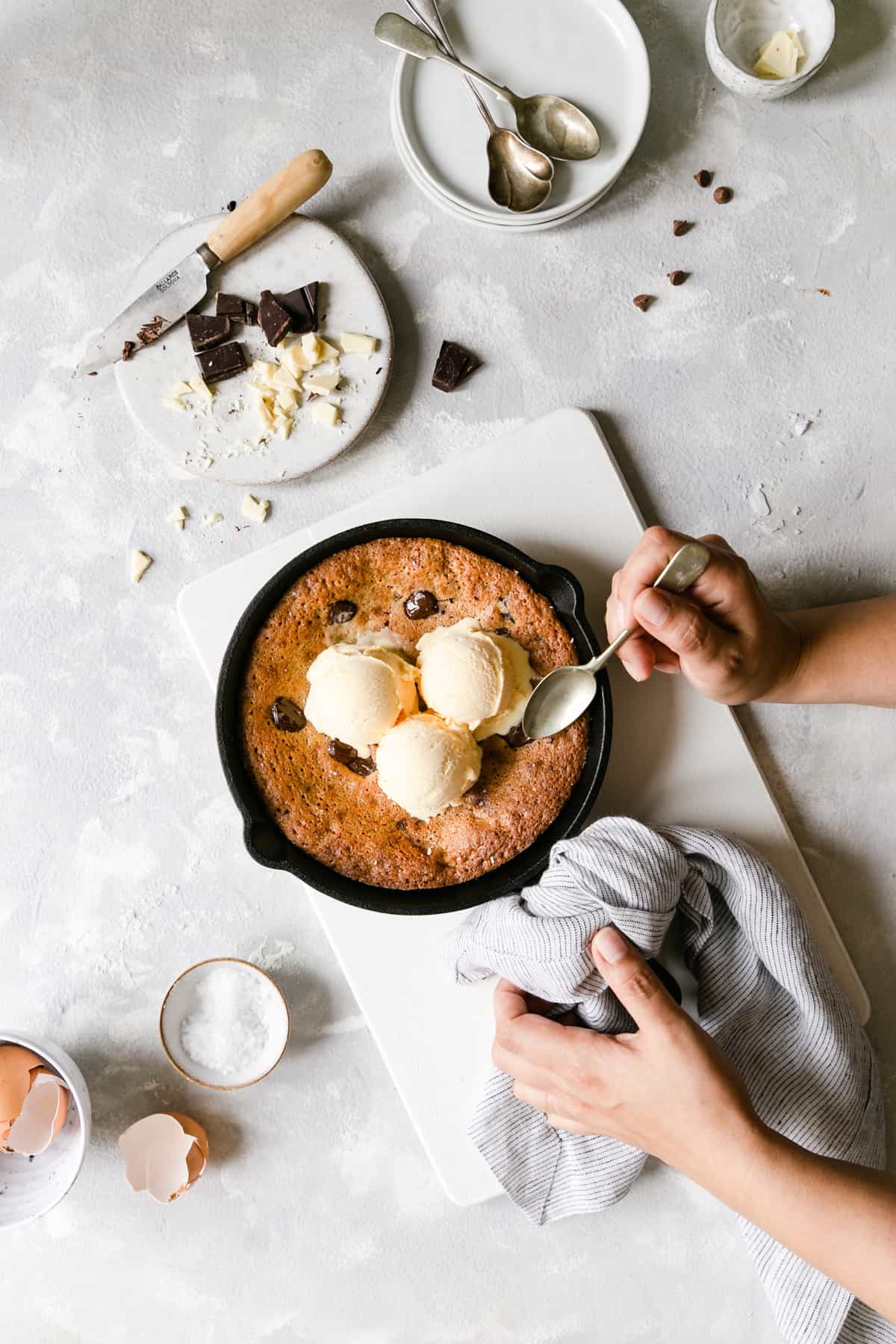 top view of a person holding skillet with chocolate chip cookie topped with vanilla ice cream